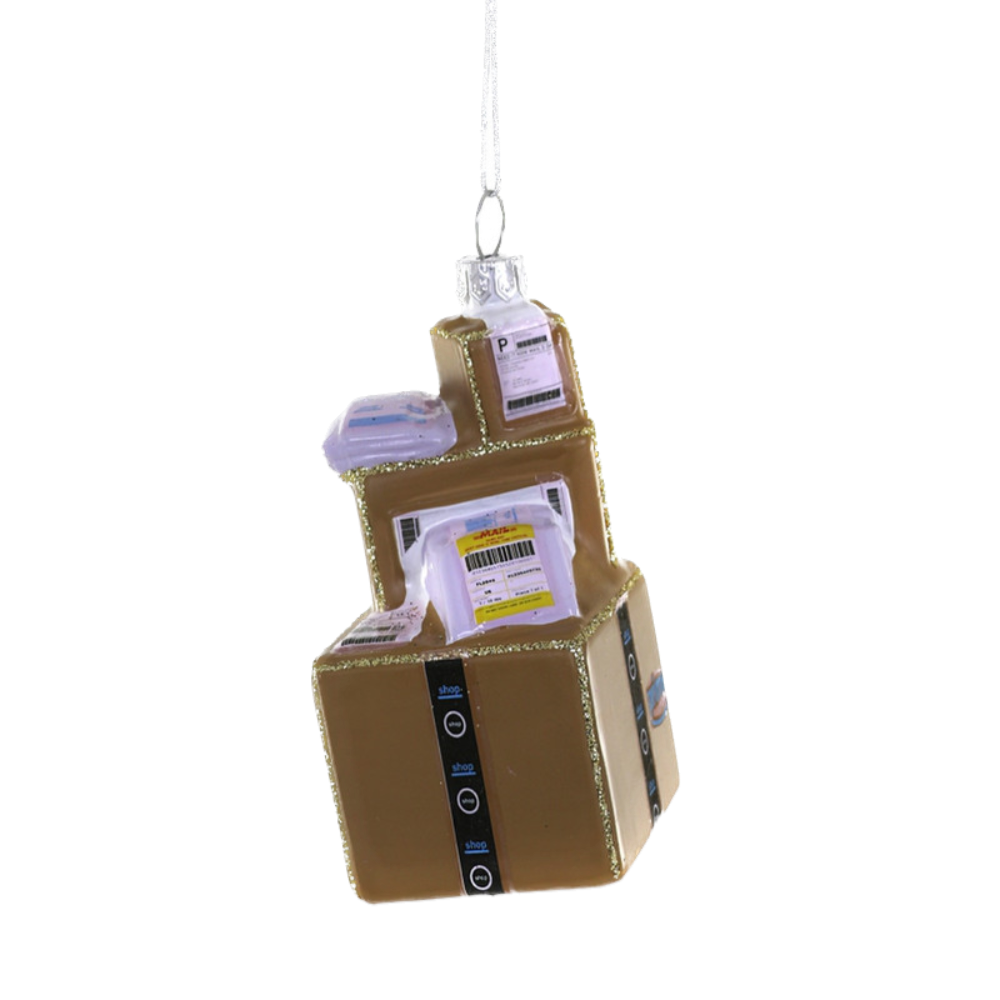 A glass holiday ornament designed to resemble an Amazon Prime shopping box, with the brand's logo and a Christmas tree ribbon.