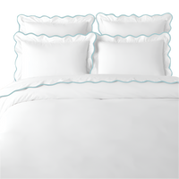 White bedding set with blue scalloped edges on a white background