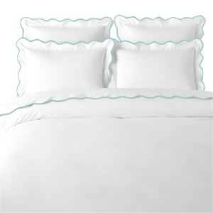 White bedding set with blue scalloped edges on a white background